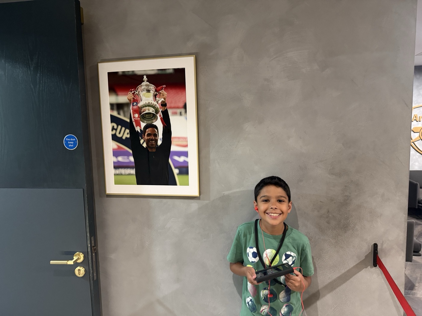 Zane smiling next to a photo of Arteta lifting a trophy